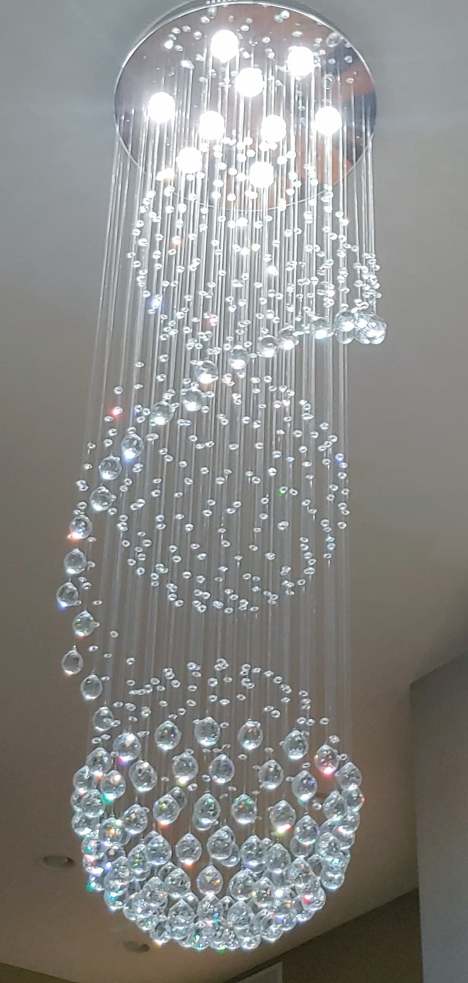 Tall crystal rain chandelier with strands of crystals ending in a sphere