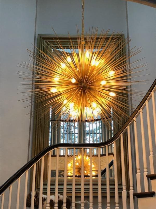 Gold sputnik chandelier with exposed bulbs hanging over a staircase