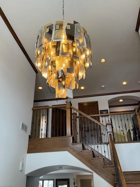 Tiered gold chandelier lit above a staircase